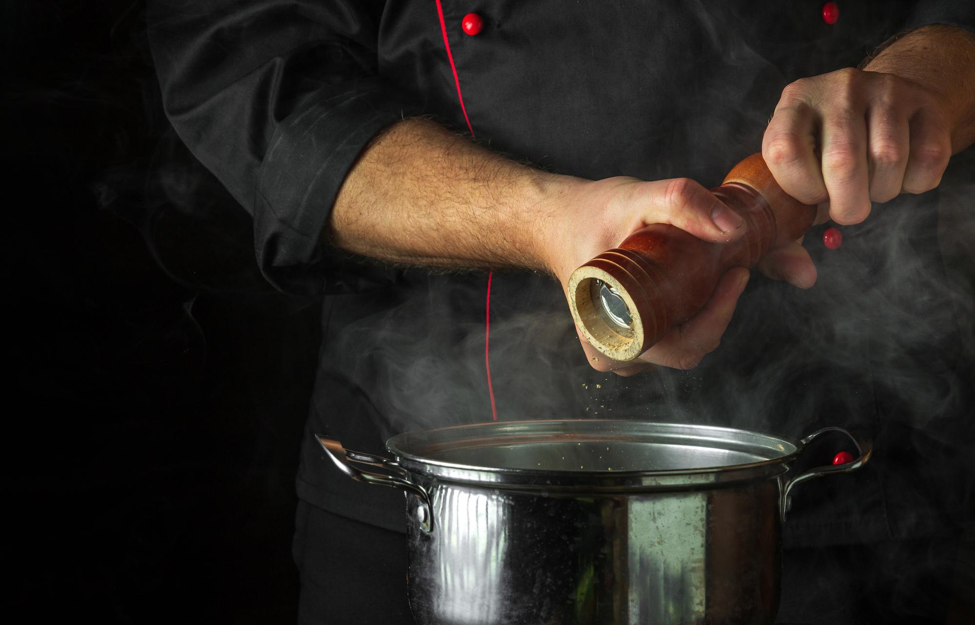 Chef finishing a sauce in brass pan